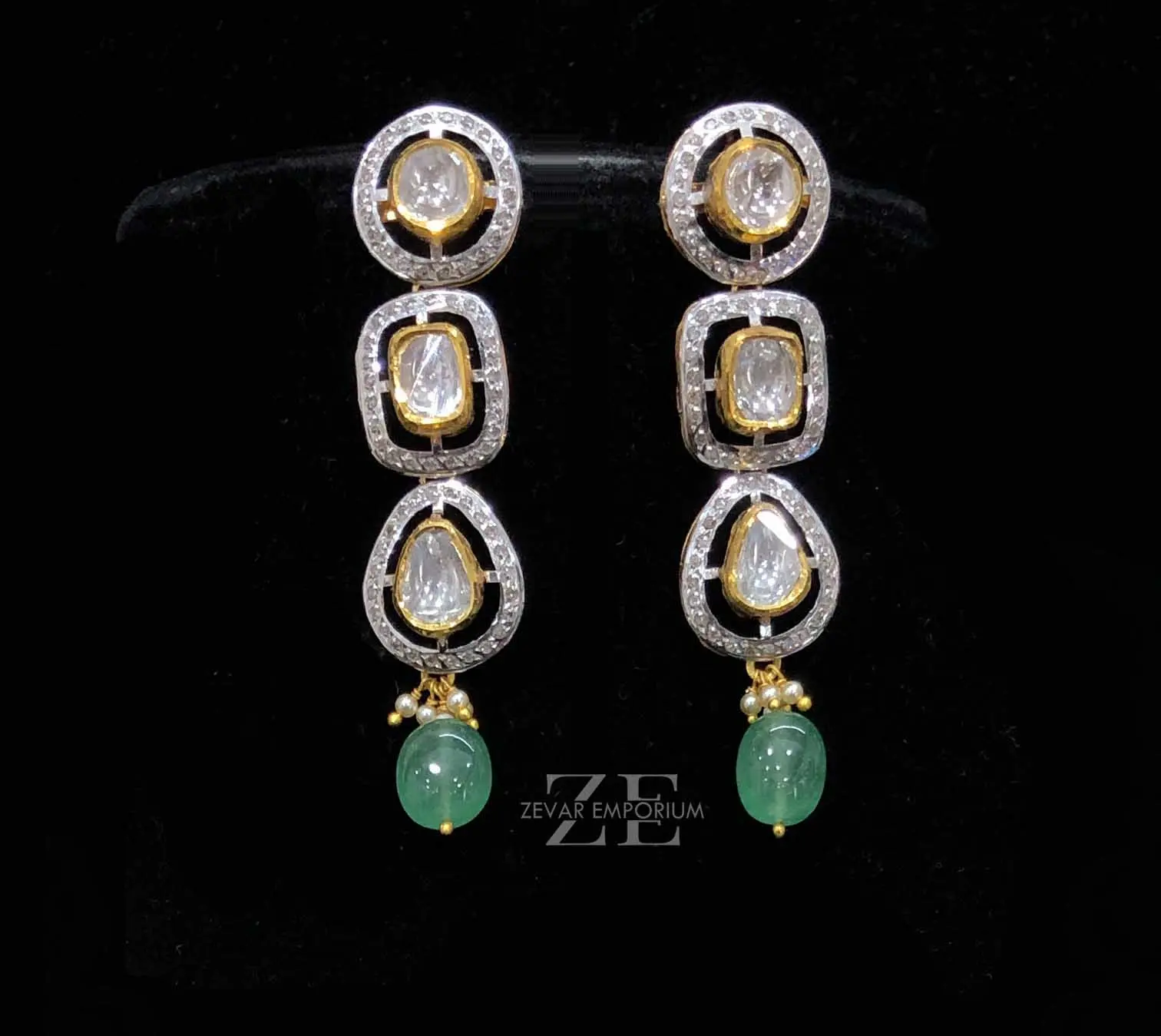 Pair of 14k gold fusion linear earrings displaying geometric polki links, round diamond settings, and emerald drops.