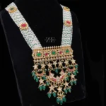 Ruby Emerald Polki Necklace featuring a grand multi-strand pearl haram with a large polki plaque and cascading emerald drops.