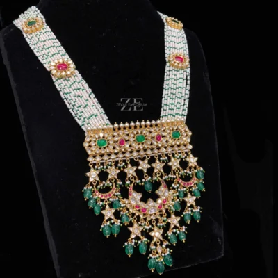 Ruby Emerald Polki Necklace featuring a grand multi-strand pearl haram with a large polki plaque and cascading emerald drops.